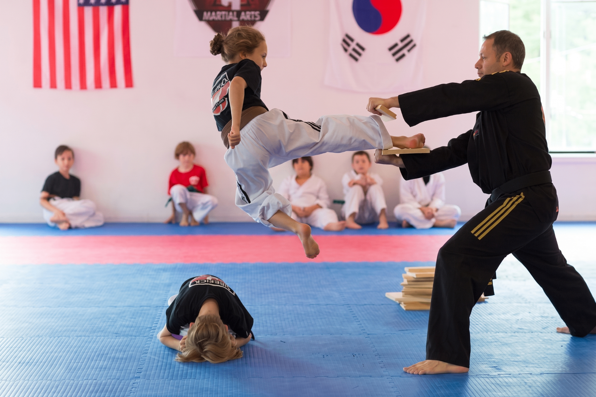 Instructor high-fiving a young karate student during class at Sidekick